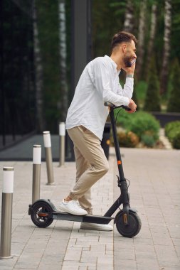 Telefonla. Şık bir adam mobiletiyle gündüz vakti dışarı çıkar..