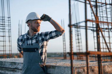 Ayakta durup ara veriyoruz. Gündüz vakti inşaatta çalışan bir adam var..