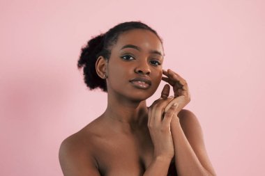 Makyaj ve güzellik kavramı. Pembe arka plana karşı olan Afrikalı Amerikalı genç bir kadının portresi.