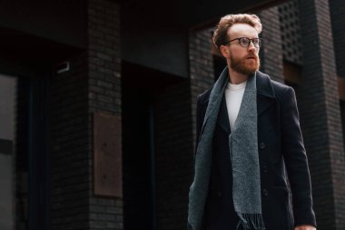 Binanın yakınında yürüyorum. Sakallı ve gözlüklü şık adam dışarıda..