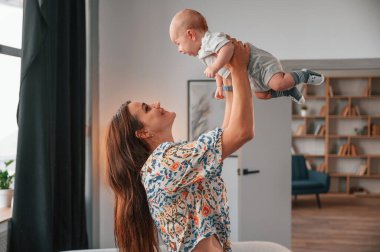 Çocuğu ellerinde tutarak. Güzel mutlu anne ve yeni doğan oğlu evde..