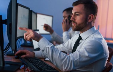 Yan görüş. Ofiste değişim teknolojisiyle çalışan iki borsacı..