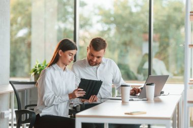 Fikirlerimizi paylaşıyoruz. Erkek ve kadın modern ofiste birlikte çalışıyorlar..