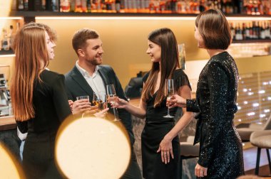 Bir grup şık giyinmiş insan restoranda kutlama yapıyor..