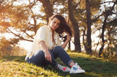 Güzel bir kadın gündüz vakti ormanda çimlerin üzerinde oturuyor..