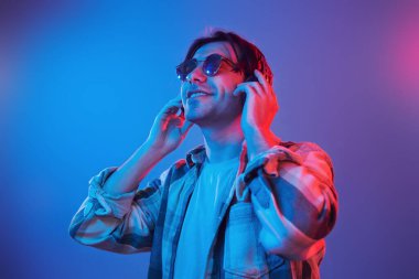 Listening to the music. Man standing in the studio with neon light.