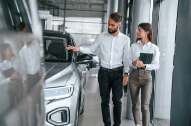 Otomobil yüzeyine dokunmak. Beyaz elbiseli bir adam araba galerisinde birlikte..