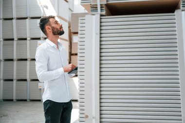 Tablet tutuluyor ve verileri kontrol ediliyor. Depo işçisi depoda bir sürü ürünle birlikte..