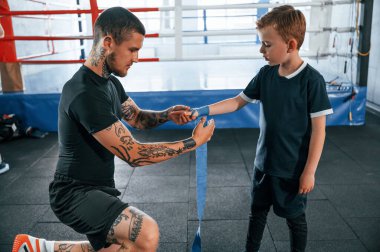 Boks kıyafetlerini giymişsin. Koç antrenman alanında oğlanla birlikte..