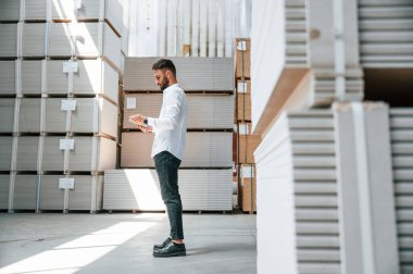 Yönetici tablet kullanarak verileri kontrol ediyor. Depo işçisi depoda bir sürü ürünle birlikte..