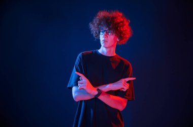 Kameraya poz veriyorum. Kıvırcık saçlı genç adam kapalı alanda neon ışıkla aydınlatılır..