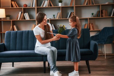 Anneler Günü kavramı. Hediye vermek. Kızıyla birlikte genç bir kadın dairede..