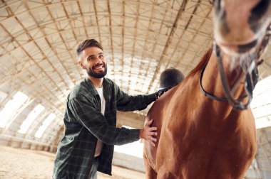 Olumlu duygular. Ön manzara. Atlı genç adam hangarda..