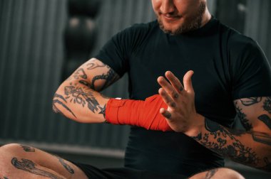 Hazır sayılırım. El bandı takıyor. Dövmeli genç adam spor salonunda boks antrenmanı yapıyor..