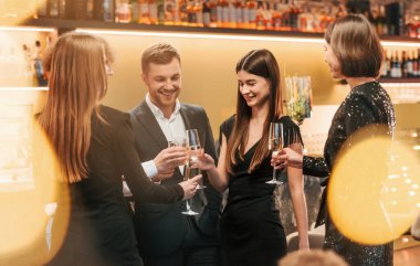 Bir grup şık giyinmiş insan restoranda kutlama yapıyor..