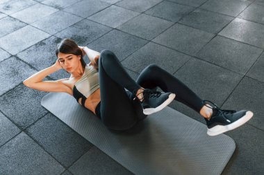 Karın kasları egzersizi yapıyorum. İnce vücutlu spor elbiseli kadın spor salonunda..