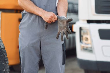 Eldiven takıyordu. Üniformalı bir adam büyük bir kamyon için hizmet veriyor..