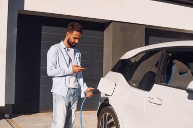 Akıllı telefonlu. Genç şık adam, gündüz vakti elektrikli arabayla geziyor..