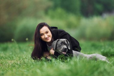 Uzanmak ve gülümsemek. Genç esmer kız köpeğiyle dışarıda yürüyüş yapıyor..