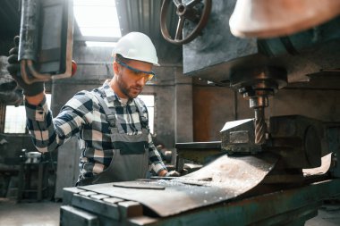 Otomatik matkabı çalıştırıyorum. Üniformalı fabrika çalışanı içeride..