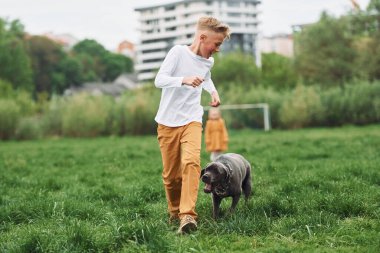 Birlikte koşmak. Küçük çocuk yaz vakti köpeğiyle dışarıda yürüyüş yaparken eğleniyor..