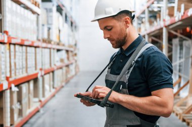 Tabletteki verileri kontrol ediyorum. Üniformalı eleman gündüz vakti depoda çalışıyor..