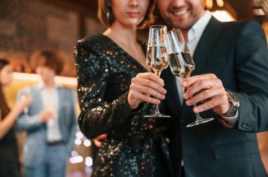 Çift poz veriyor. Güzel giyinmiş bir grup insan içeride yeni yılı kutluyorlar..