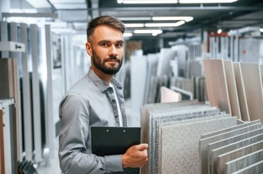 Elinde not defteriyle dikiliyorsun. Tarz sahibi güzel adam ev için malzeme deposunda..