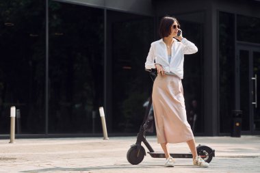 Telefonla. Güzel, genç bir bayan dışarıda motosikletiyle bekliyor..