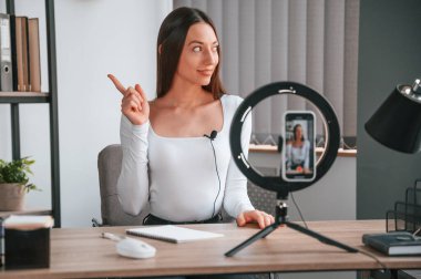 Konuşmak, online master dersi almak. Beyaz elbiseli genç ve güzel bayan ofiste..