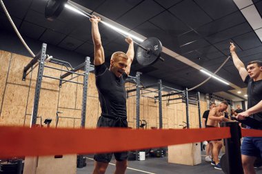 Yüz ifadesini deniyorum. Güçlü adam spor salonunda halteri kaldırıyor..