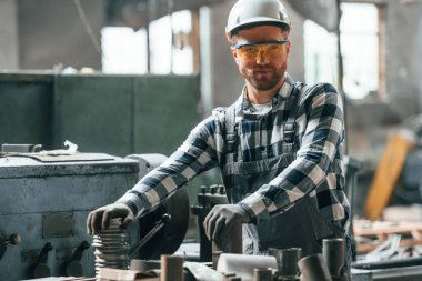 Kasketli. Üniformalı fabrika çalışanı içeride..