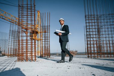 Kağıdı plan ve tabletle tutarak. Resmi kıyafetli bir işadamı gün içinde şantiyede olacak..
