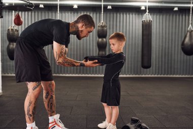 Yan görüş. Koç çocuklara kapalı alanda boks teknikleri öğretiyor..