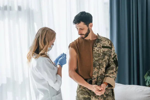 Stock image Soldier get vaccinated by female doctor indoors.