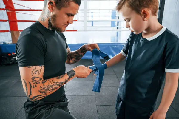 stock image Wearing the boxing hand wraps. Coach is with boy in the practice space.