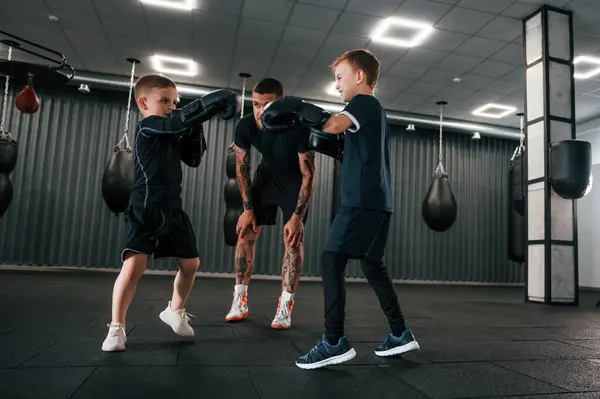 stock image Having fun by practicing. Young tattooed coach teaching the kids boxing techniques.