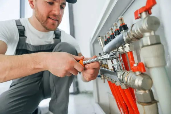 stock image Working with pipes. Repairman is working indoors in the modern room.