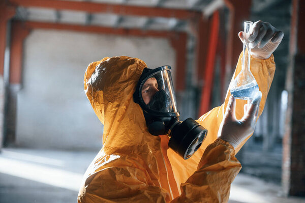 Examining radioactive liquid. Man dressed in chemical protection suit in the ruins of the post apocalyptic building.