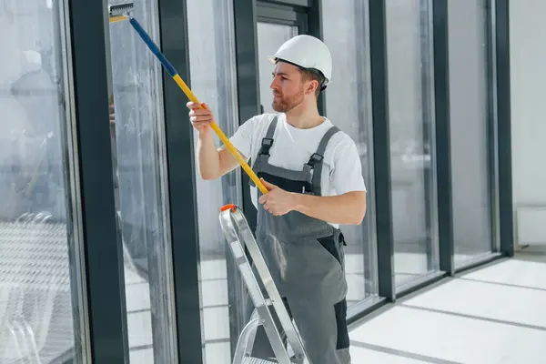 stock image Cleaning dirty windows. Repairman is working indoors in the modern room.