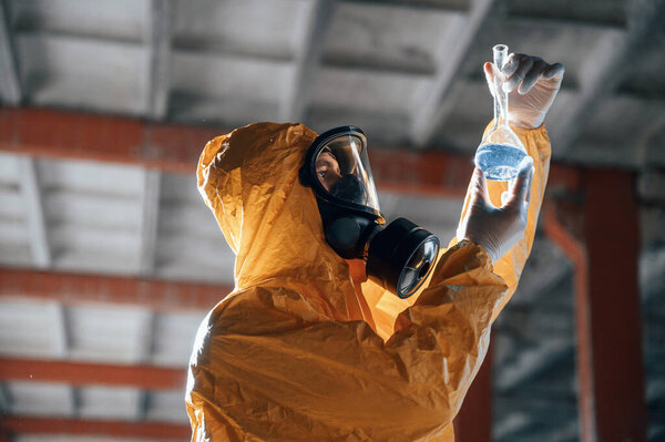 Examining radioactive liquid. Man dressed in chemical protection suit in the ruins of the post apocalyptic building.