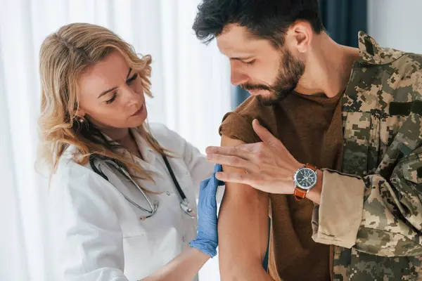 stock image Soldier get vaccinated by female doctor indoors.