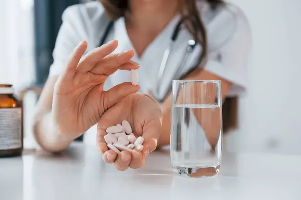 stock image Pills and glass of water. Professional medical worker in white coat is in the office.