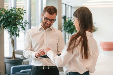 Resmi giyinmiş kadın ve erkek içeride birlikte çalışıyorlar..