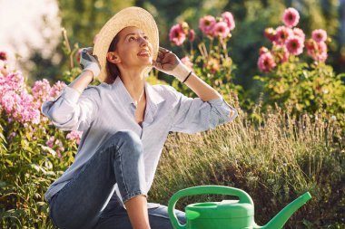 Yeşil su bidonuyla. Genç, neşeli kadın gündüz vakti bahçede..