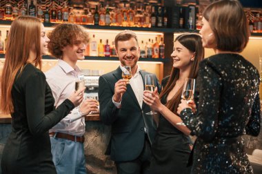 Konuşmak, gülümsemek, eğlenmek. Güzel giyinmiş bir grup insan içeride yeni yılı kutluyorlar..