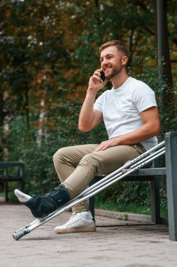 Oturup telefonla konuşuyorum. Koltuk değnekli adam dışarıdaki parkta. Bacağımdan yaralandı..