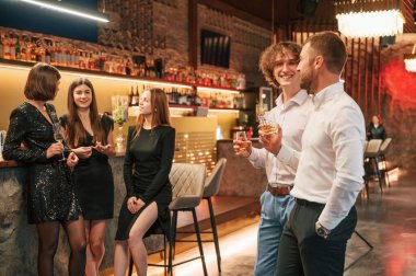 Partide iki adam ellerinde alkollü içeceklerle dikiliyorlar..