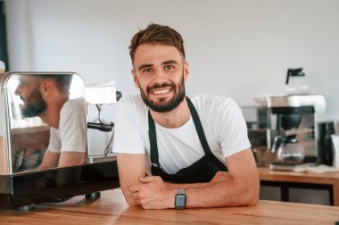 Güzel bir portre. Beyaz gömlekli ve siyah önlüklü kafe çalışanı içeride..