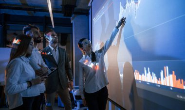 Tableti tutuyorum. Erkek lider çalışanlarla konuşuyor. Borsa şirketinin projektörüyle ilgili planı gösteriyor..